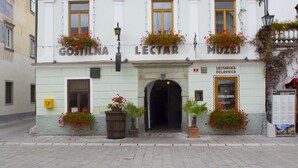 A building with the name "GOSTILNA" and "LECTAR" on the facade, featuring flower boxes on the windowsills and a door entrance. - Gostilna Lectar (Radovljica)