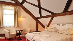 A bedroom with a bed, two chairs, a small table, and a nightstand with a lamp. - Gostilna Lectar (Radovljica)