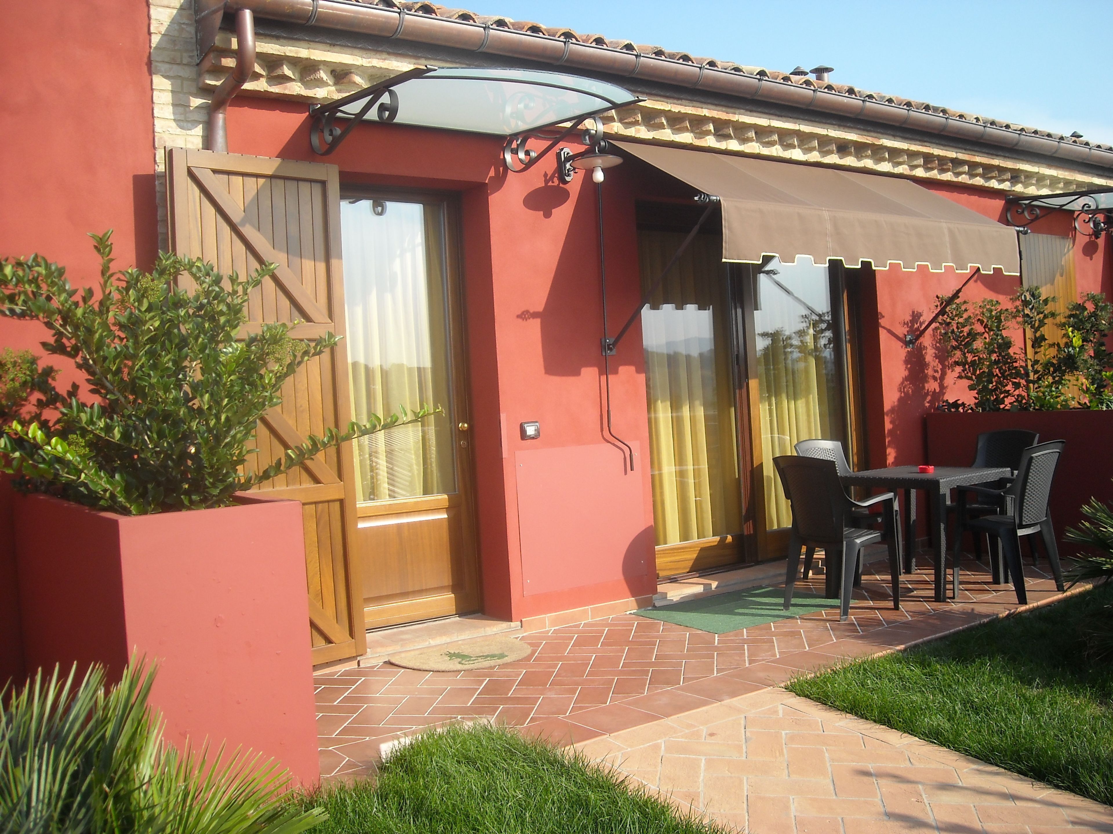 A patio area with a table and chairs, a wooden door, and a covered entrance.
