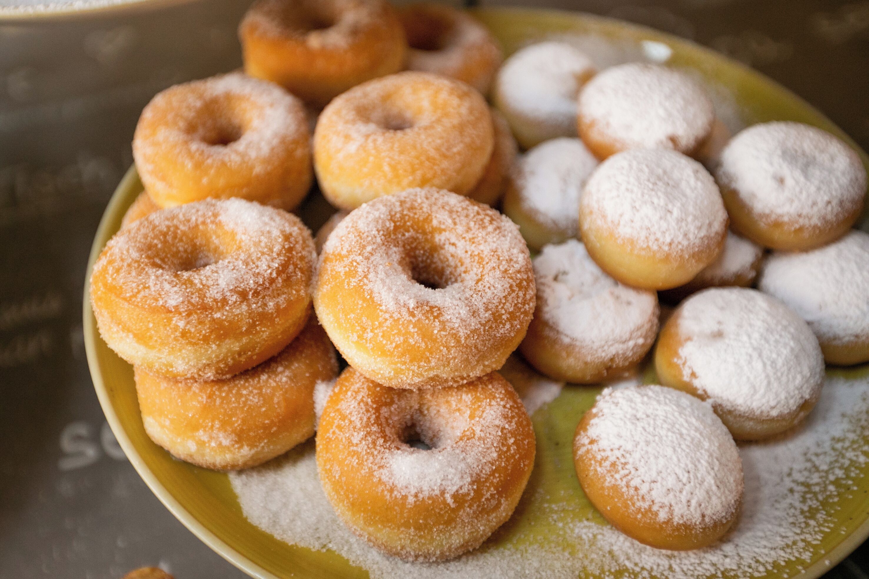 A plate of assorted doughnuts, some coated with sugar.