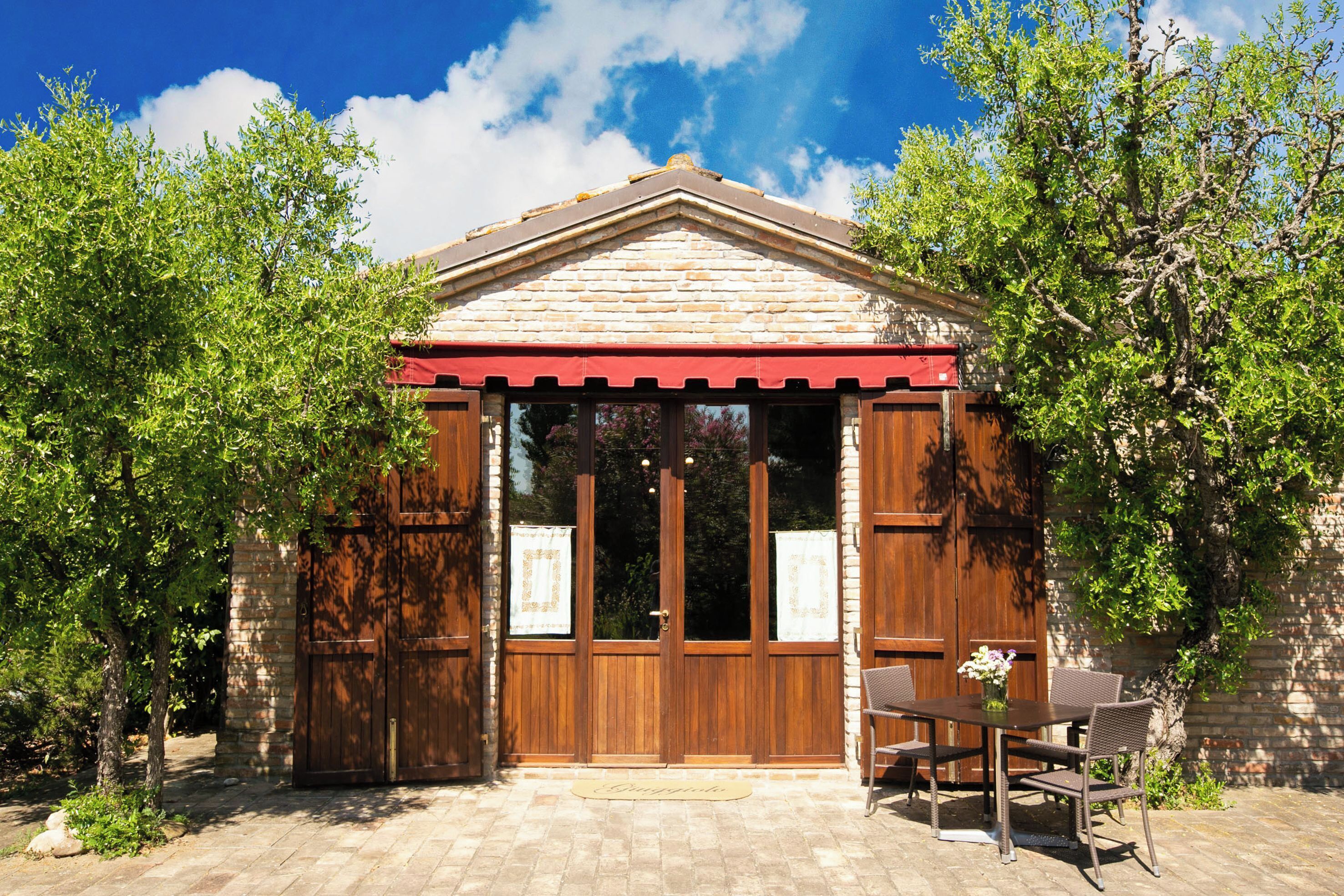 A small building with a wooden facade, large glass doors, and a red awning.