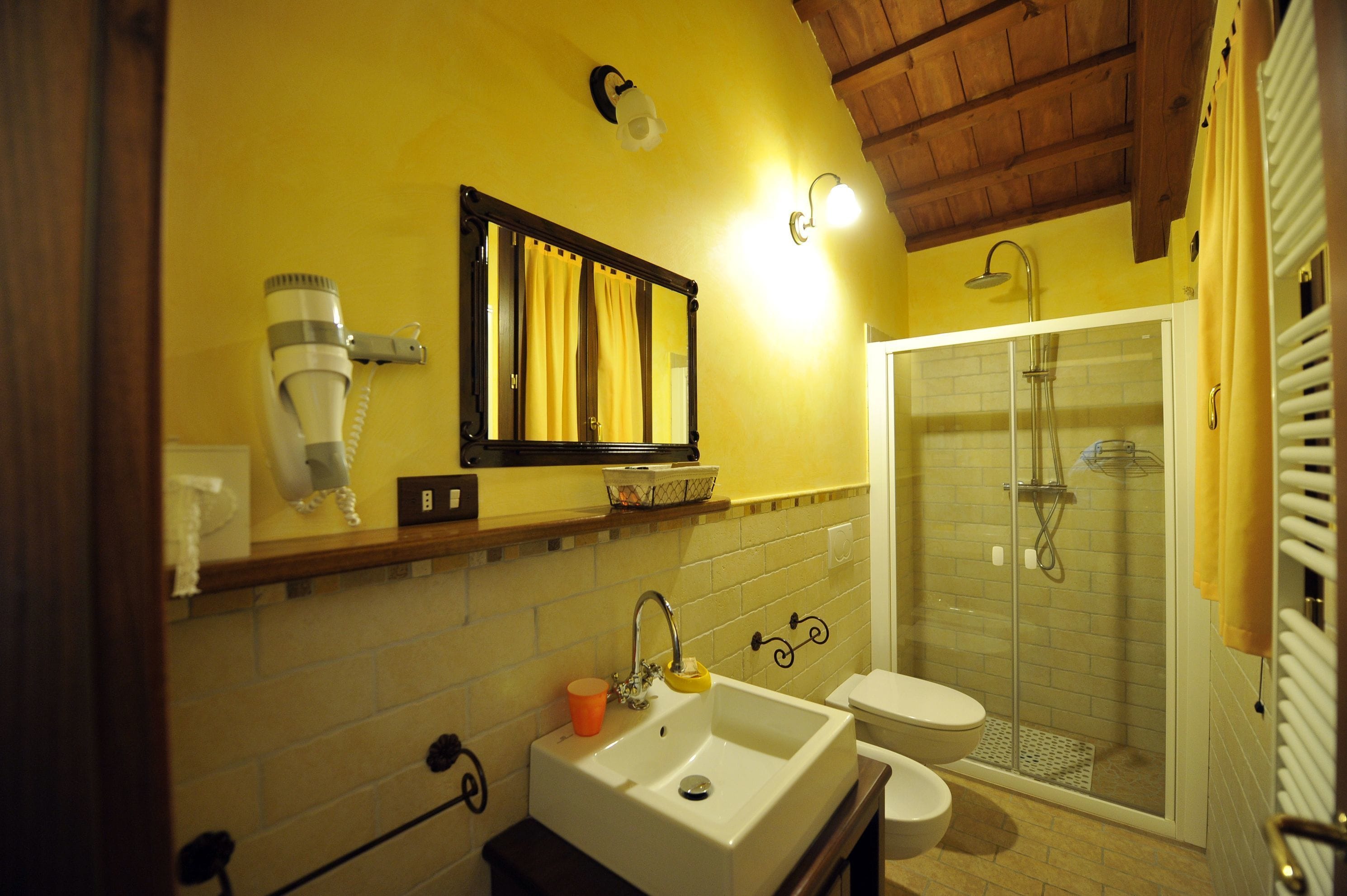 A bathroom with a sink, mirror, shower, and toilet.