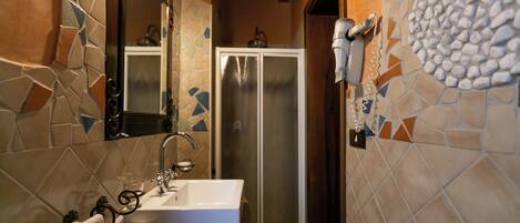 Un baño con pared de azulejos, un lavamanos, un espejo, una toalla y una puerta de ducha.
