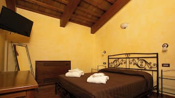 A hotel room with a bed, a desk, a television, and a wall-mounted light fixture.