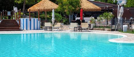 Piscina all'aperto, una piscina a sfioro, lettini