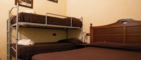 A dormitory room with bunk beds, a wooden headboard, and two framed pictures on the wall.