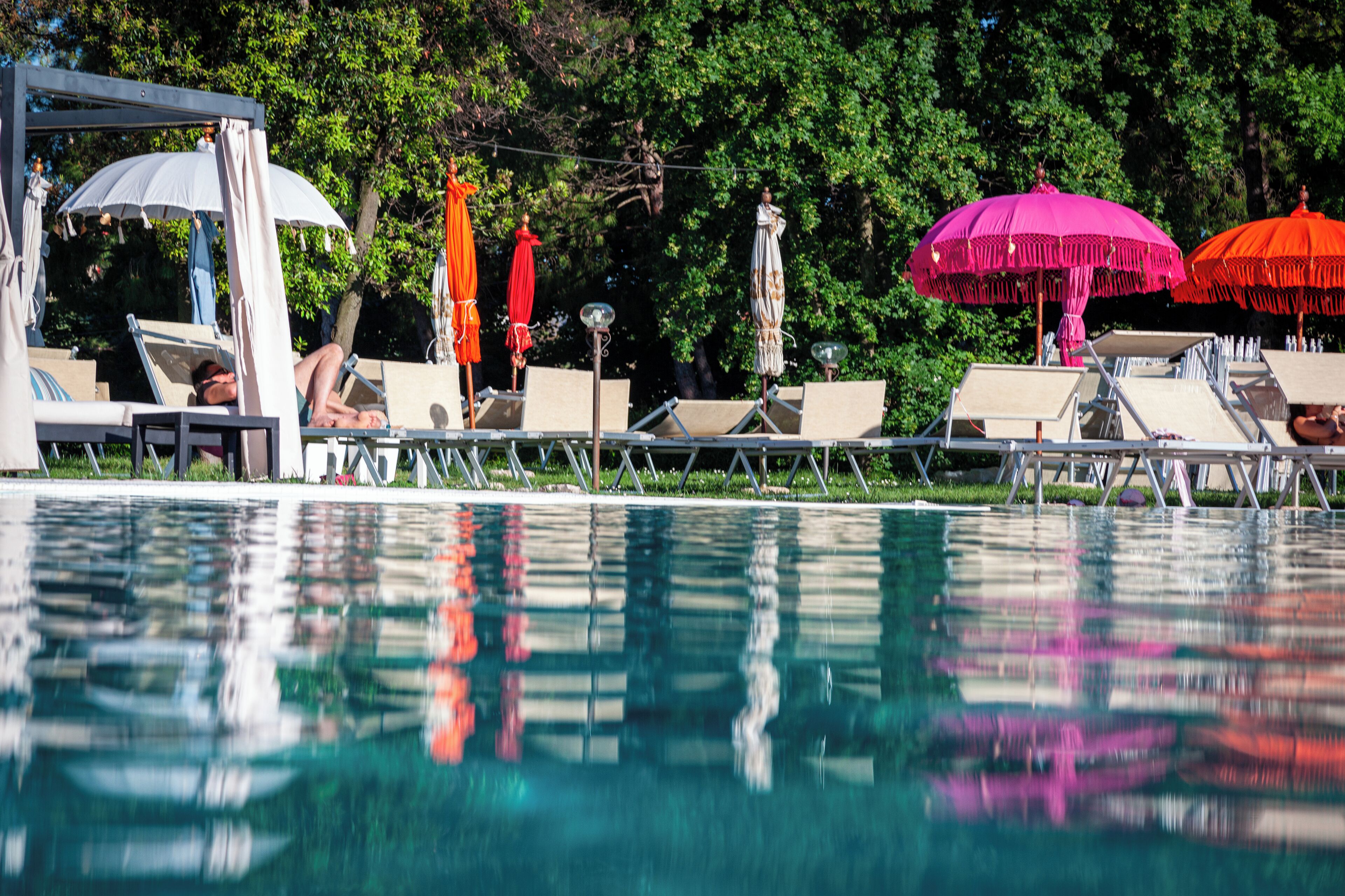 Uma área de piscina com espreguiçadeiras e guarda-sóis.