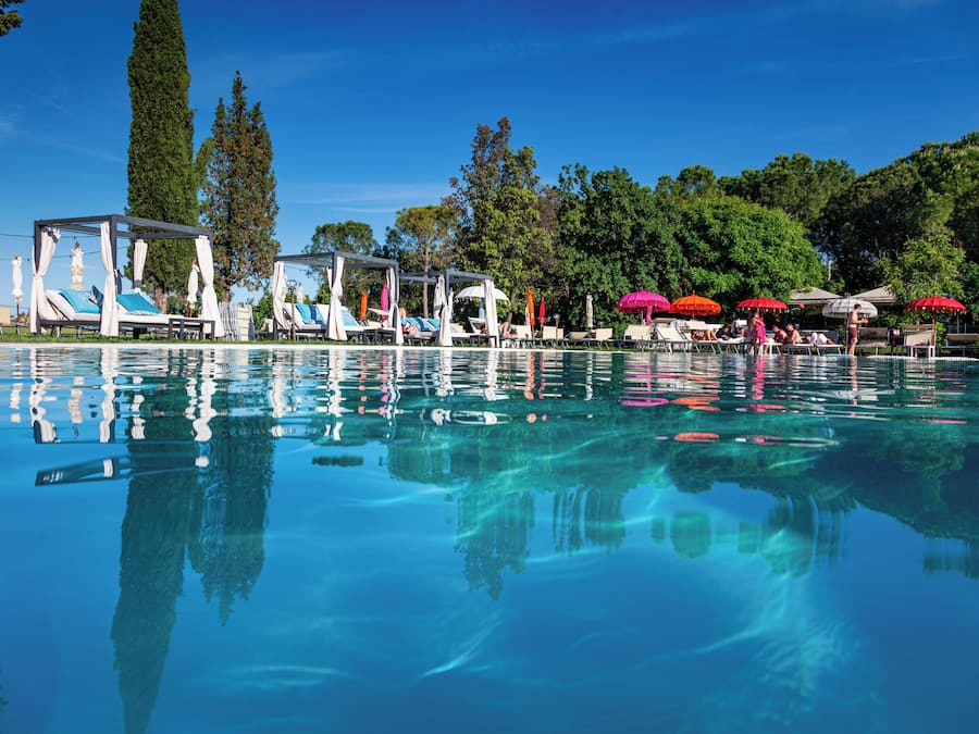 Una piscina al aire libre, una piscina con borde infinito, tumbonas