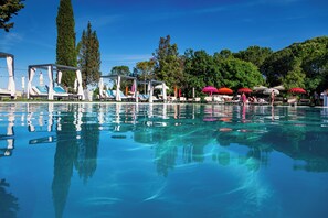 A clear swimming pool with lounge chairs and umbrellas, surrounded by trees. - Podere del Germano Reale (Coriano)