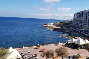 A coastal hotel with a view of the sea, outdoor seating, and a paved walkway. - Hotel Roma (Sliema)