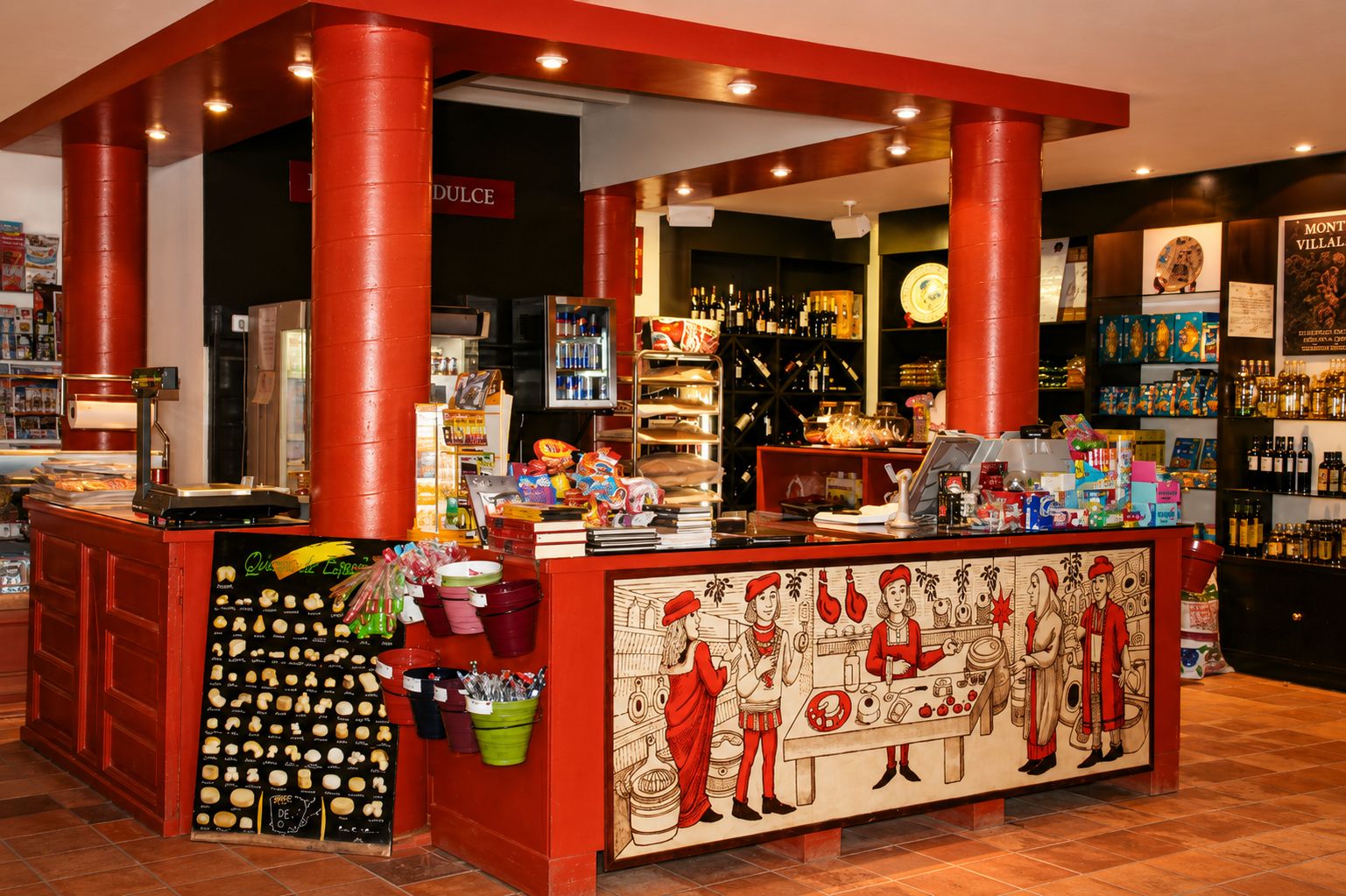 Een bar met een rode toonbank, planken vol flessen en een muurschildering met afbeeldingen van historische figuren.