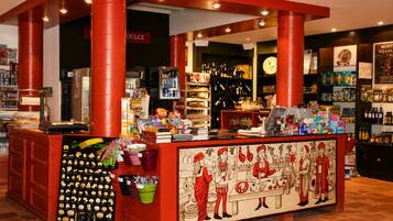 Een bar met een rode toonbank, planken vol flessen en een muurschildering met afbeeldingen van historische figuren.