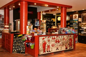 Zona de bar con mostrador rojo, estantes con botellas y un mural que representa figuras históricas.