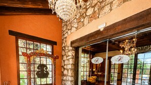 Una habitación con pared de piedra, un banco de madera, un tapiz grande y una araña.