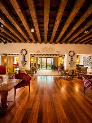 A spacious room with wooden flooring, a red sofa, and multiple chairs. - Hotel El Rancho (Torrecaballeros)