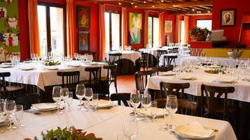 Un restaurante con varias mesas dispuestas para comer, con una pared roja decorada con obras de arte y un techo de madera.