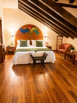 Una habitación de hotel con una cama grande, un banco de madera, un escritorio y una silla.
