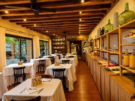 Un restaurante con mesas dispuestas para comer, techo de madera y estantes con cristalería y vajilla.