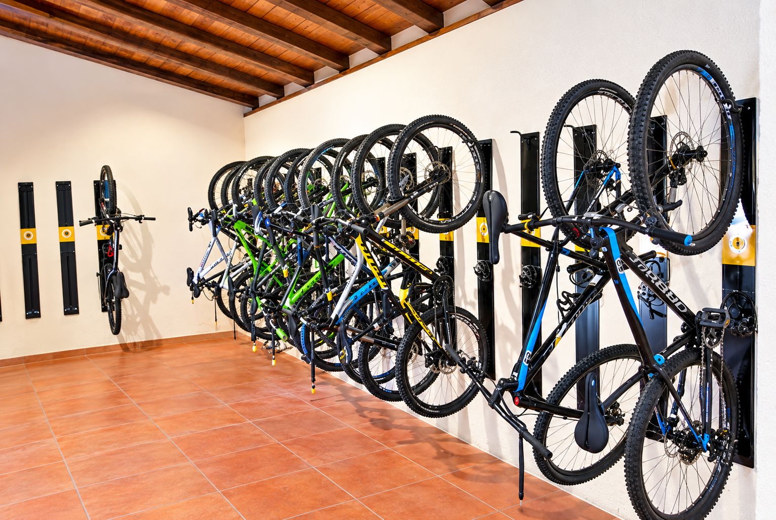 Una habitación con piso de baldosas y un perchero de bicicletas instalado en la pared, con varias bicicletas.