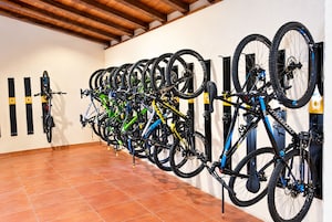 Una habitación con piso de baldosas y un perchero de bicicletas instalado en la pared, con varias bicicletas.