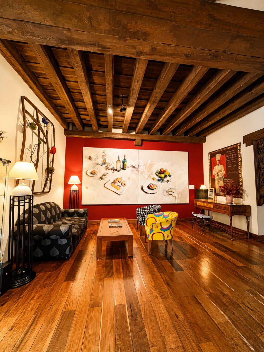 Una habitación con techo de madera, un sofá, una silla, una mesa y un cuadro grande en la pared.