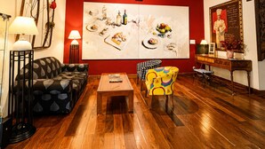 Una habitación con techo de madera, un sofá, una silla, una mesa y un cuadro grande en la pared.