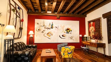 Una habitación con techo de madera, un sofá, una silla, una mesa y un cuadro grande en la pared.