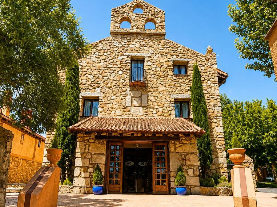 Un edificio de piedra con una cruz en la parte superior, un campanario y una entrada con tejas.
