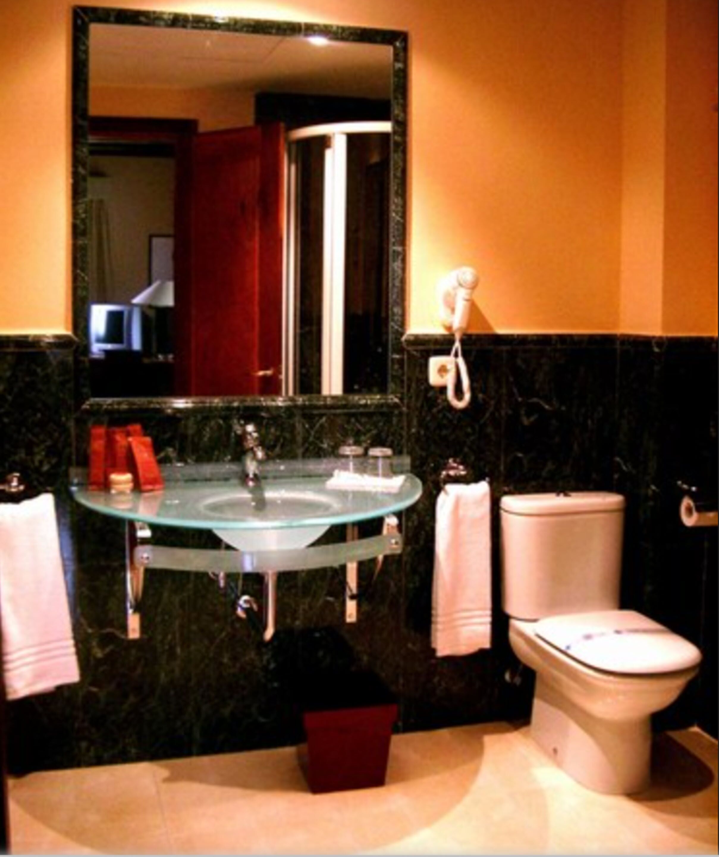 Een badkamer met een glazen wastafel, toilet en spiegel.