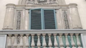 A building facade with a decorative archway, a balcony with balustrades, and a window with shutters. - La Luna Guesthouse (Florence)