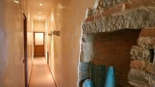 A hallway with a stone fireplace, a tiled floor, and a door at the end. - La Luna Guesthouse (Florence)