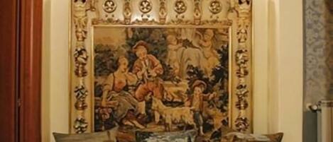Una habitación con un cuadro grande y ornamentado en la pared, una puerta de madera y un tapete estampado en el suelo.
