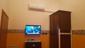 A bathroom with a television mounted on the wall, a cabinet, and a radiator. - La Luna Guesthouse (Florence)