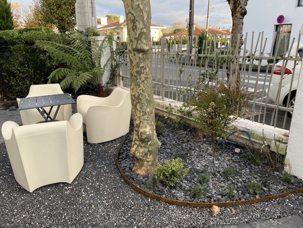 A patio area with outdoor seating, a tree, and a gravel path.