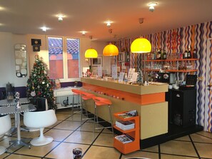 A bar area with a Christmas tree, orange bar stools, and a patterned wall. - Mirano (Biarritz)
