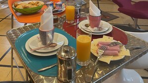 Estratègia de esmorzar amb una taula preparada per a dues persones, incloent plats, coberts, una forquilla de cafè i un bol de pastissos.