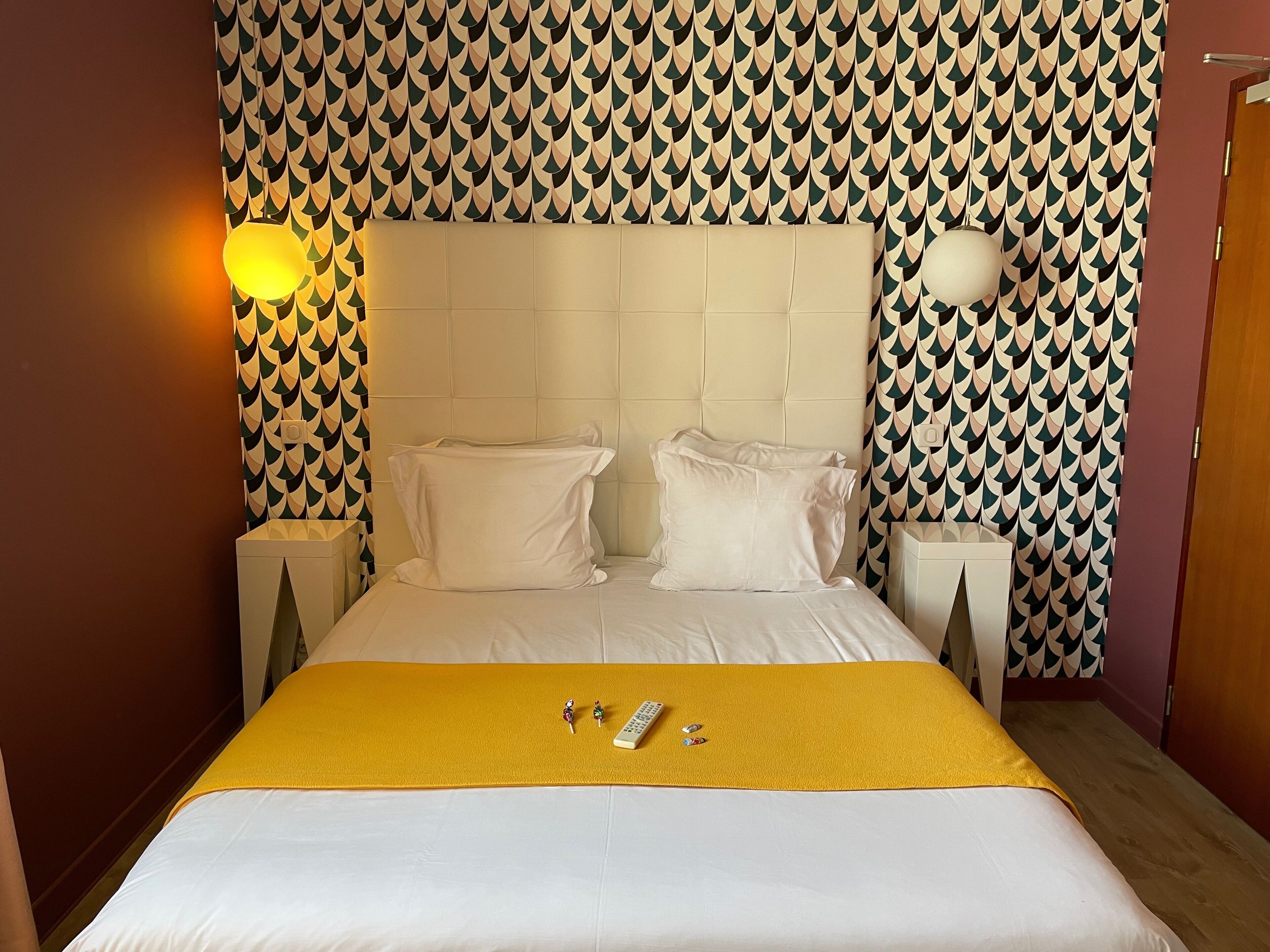 A neatly made bed with white bedding, two pillows, and a yellow throw blanket.