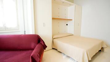 Um quarto com uma cama, um sofá vermelho e um guarda-roupa com espelho.