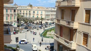 A courtyard with buildings, a white car, and people. - Residence Arco Antico (Syracuse)