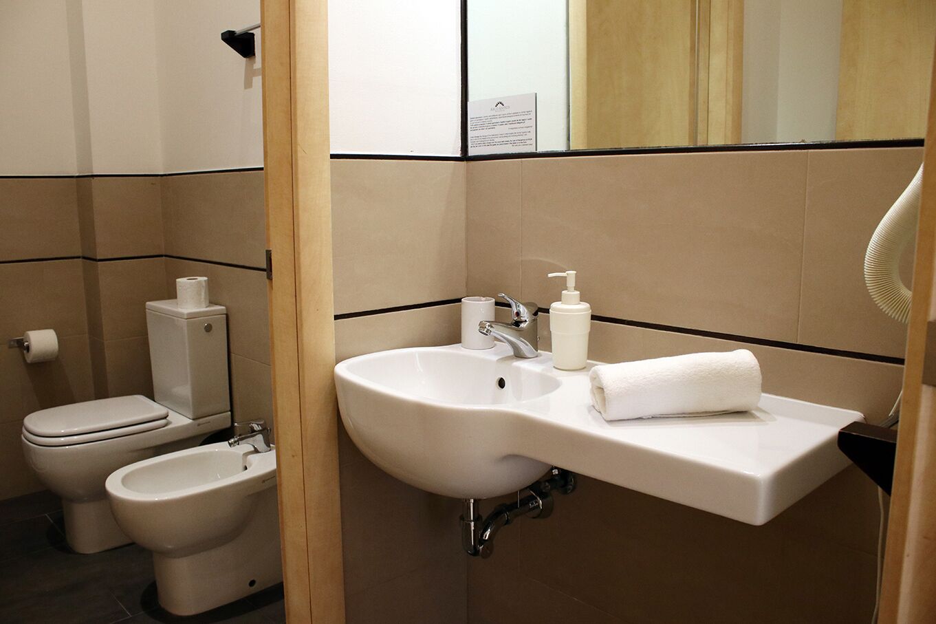 Un baño con lavamanos, inodoro, bidé y una toalla sobre la encimera.