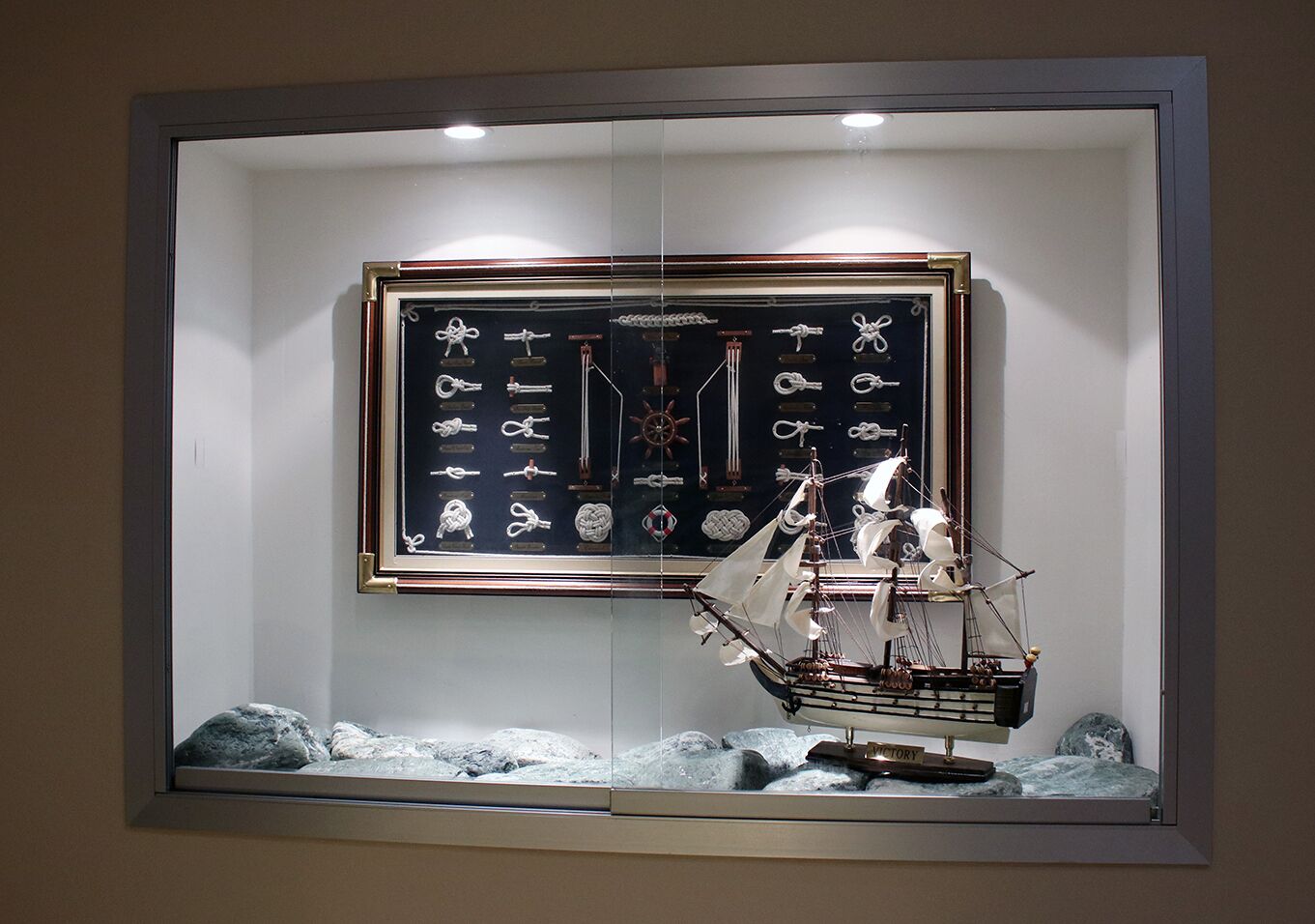 Ein gerahmtes Display mit nautischen Gegenständen, darunter Schiffmodelle und Seile.