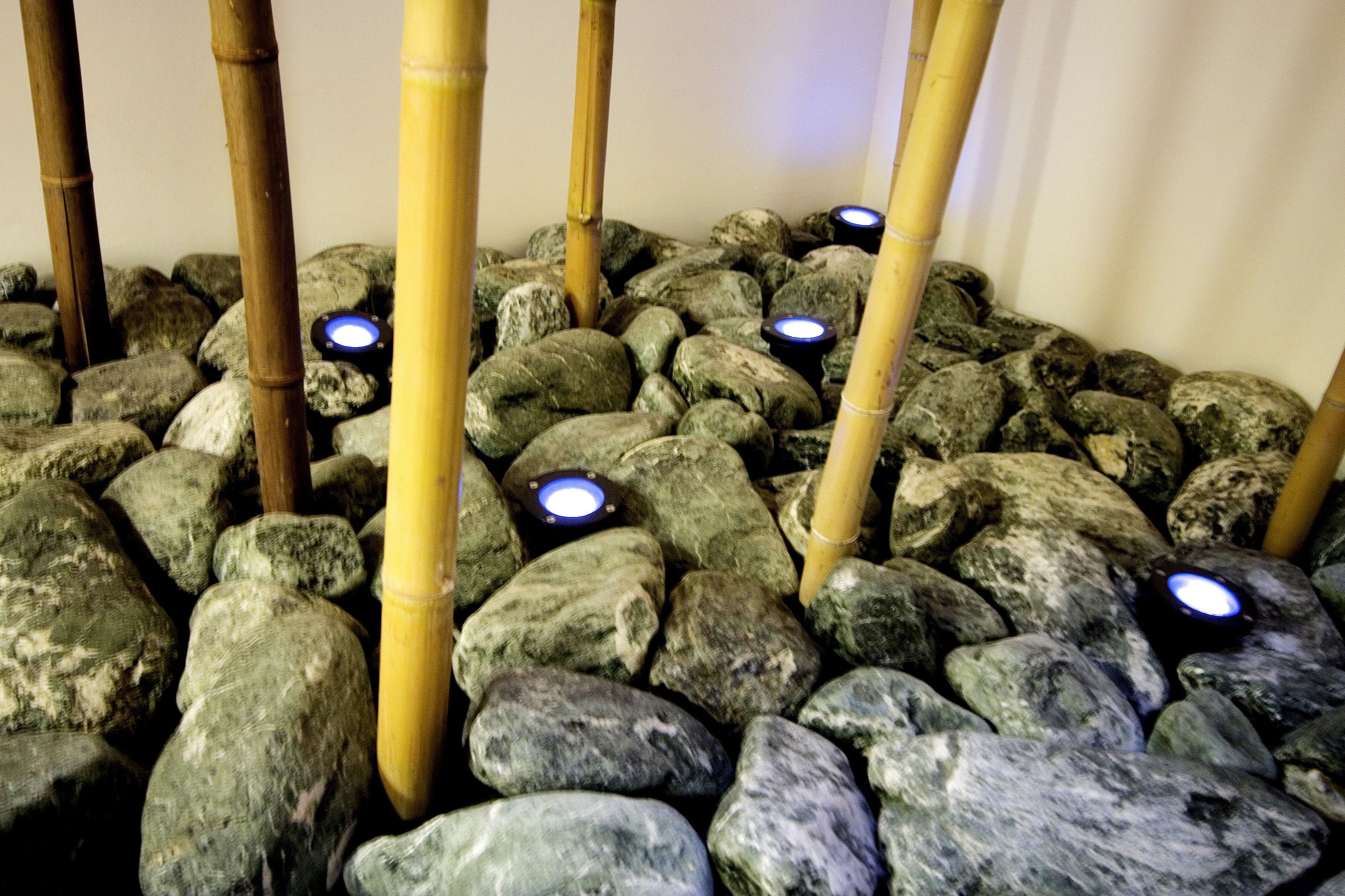 Un giardino roccioso con pilastri di bambù e pietre illuminate.