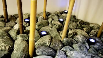 Un giardino roccioso con pilastri di bambù e pietre illuminate.
