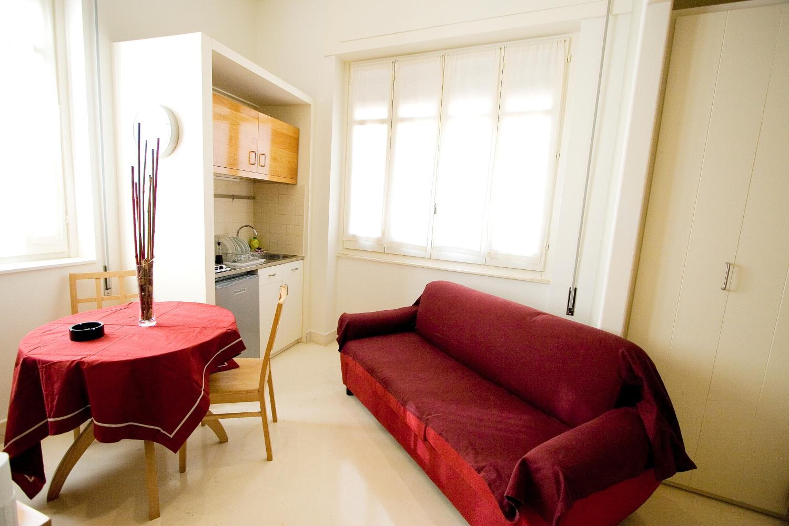 Un espacio habitable compacto con una mesa de comedor, un sofá y una kitchenette.