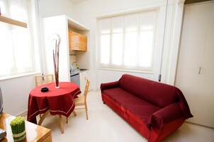 Ein gemütlicher Wohnbereich mit Esstisch, einem roten Sofa und einer Küchenzeile.