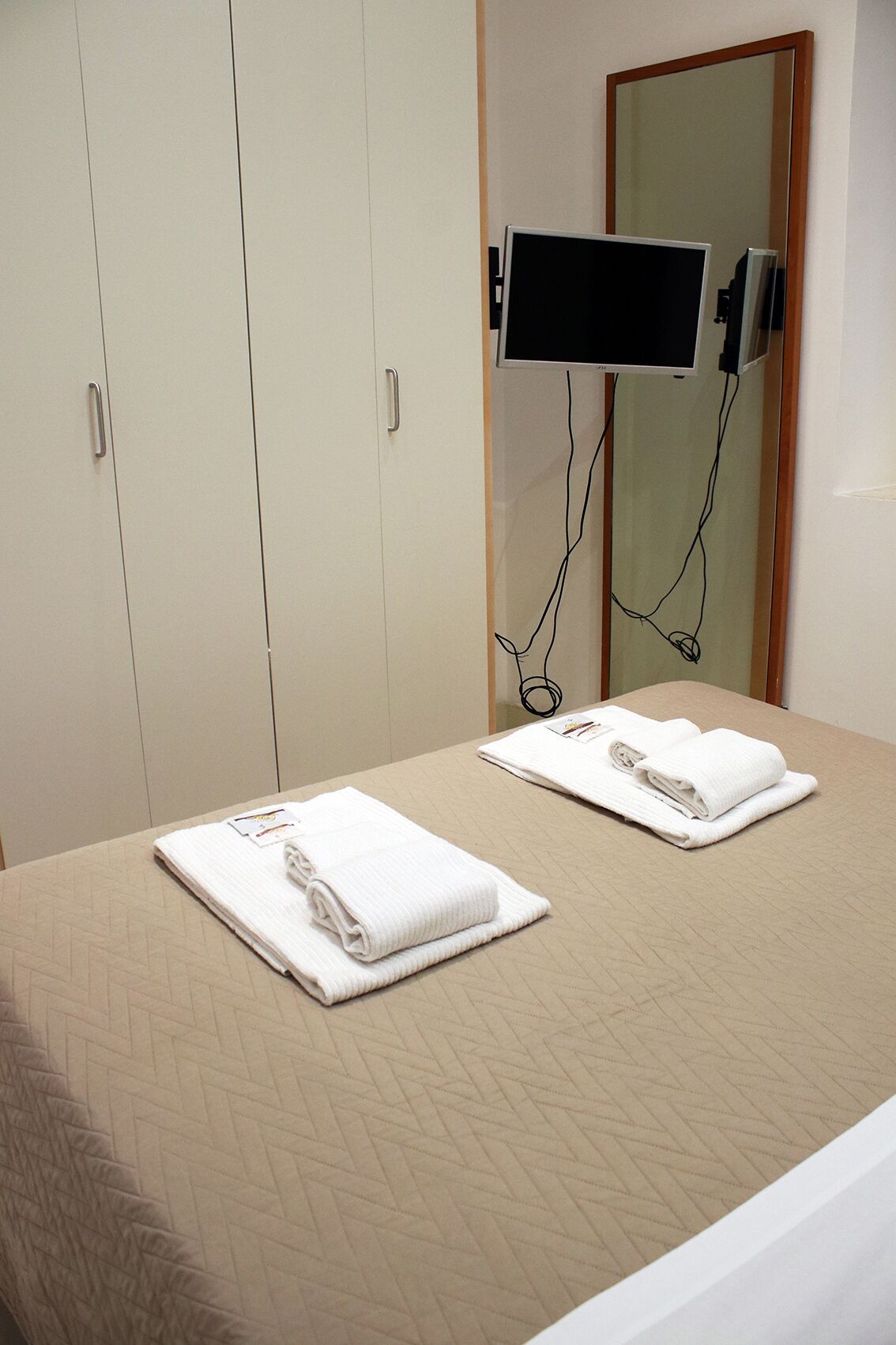 Ein Hotelzimmer mit Bett, Wandfernseher und Spiegel.