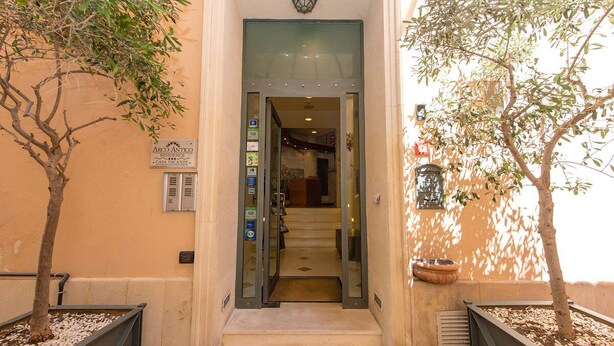A hotel entrance with a glass door, a staircase leading inside, and two potted trees on either side. - Residence Arco Antico (Syracuse)