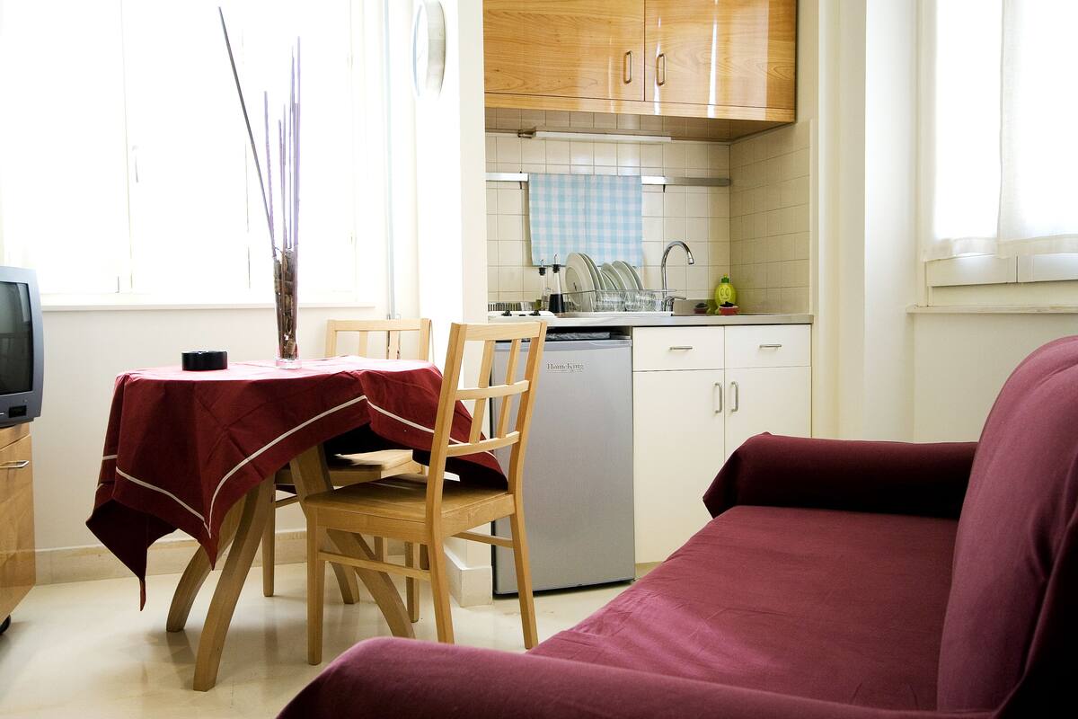 A compact living space with a dining area, kitchenette, and a sofa.