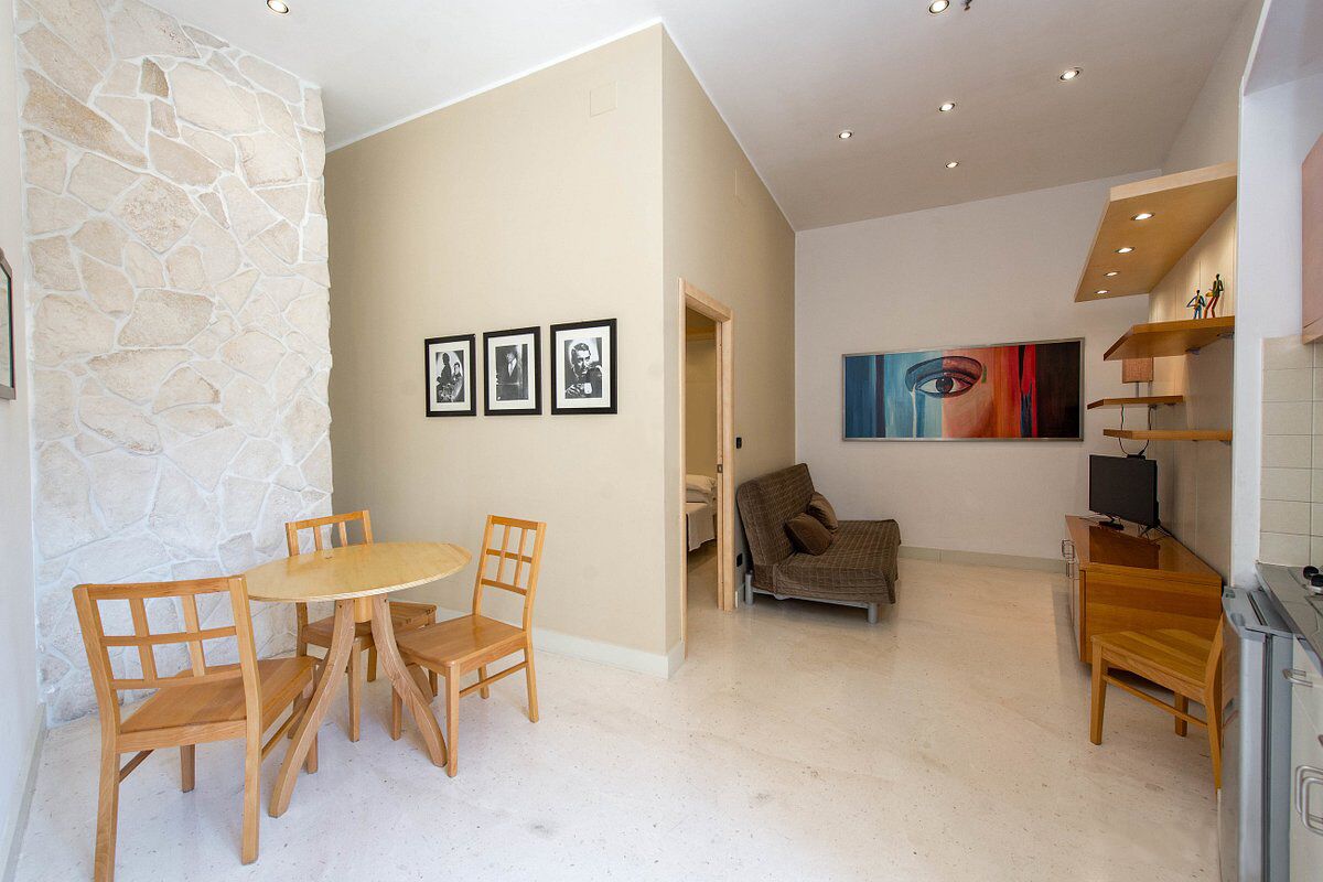 Un salon moderne avec un mur en pierre, un coin repas avec des meubles en bois et un grand tableau accroché au mur.