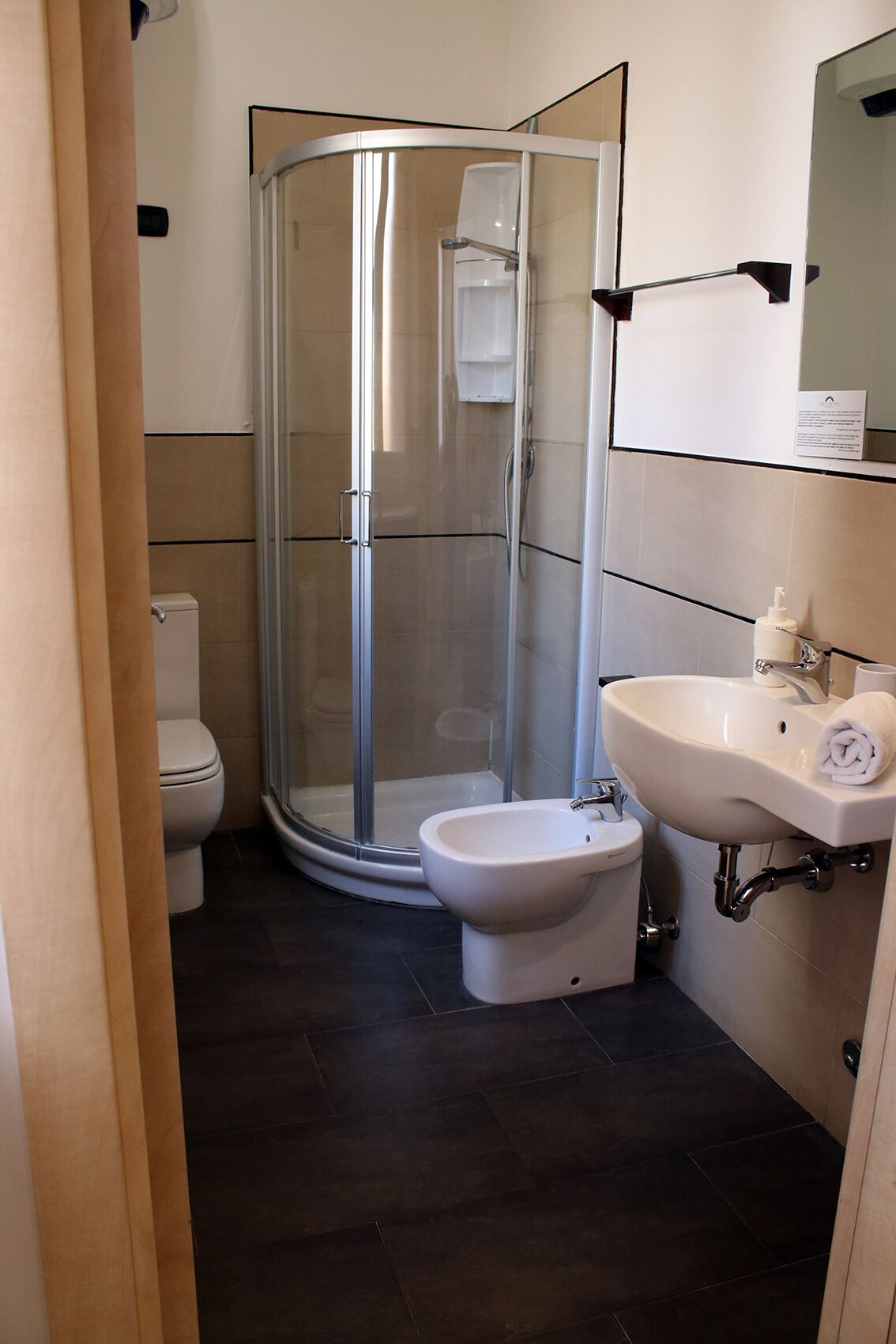 A modern bathroom with a glass-enclosed shower, a bidet, a toilet, and a sink with a mirror above it.